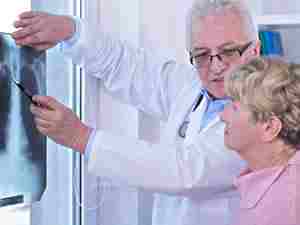 Cancro al polmone: il medico mostra alla sua paziente la radiografia al torace 